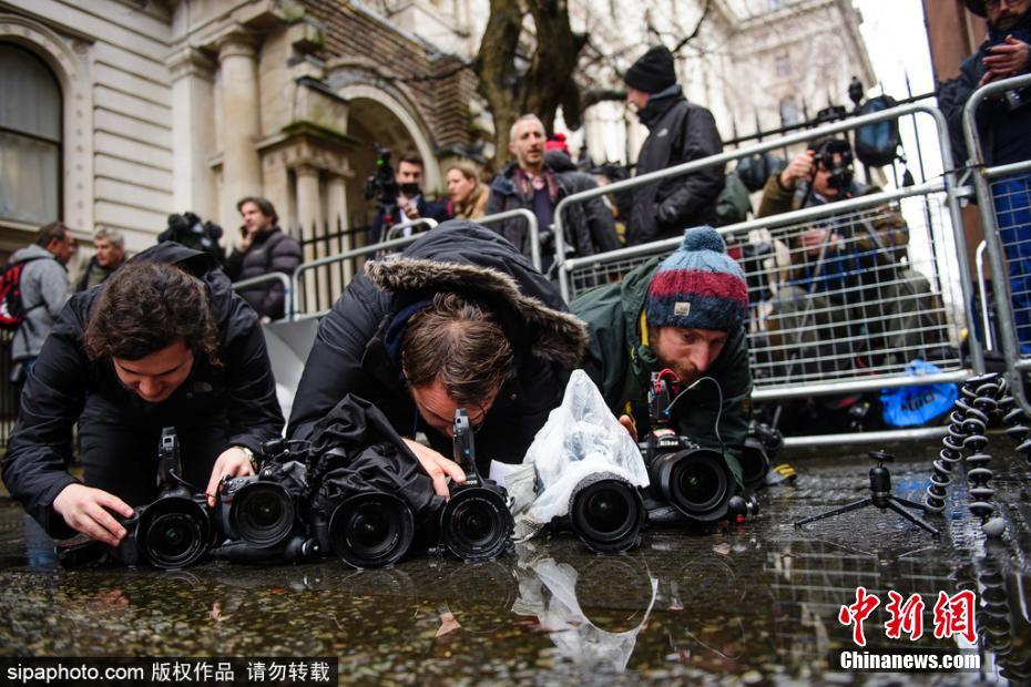 英国公布脱欧预算报告 记者趴水坑拍照也是够拼