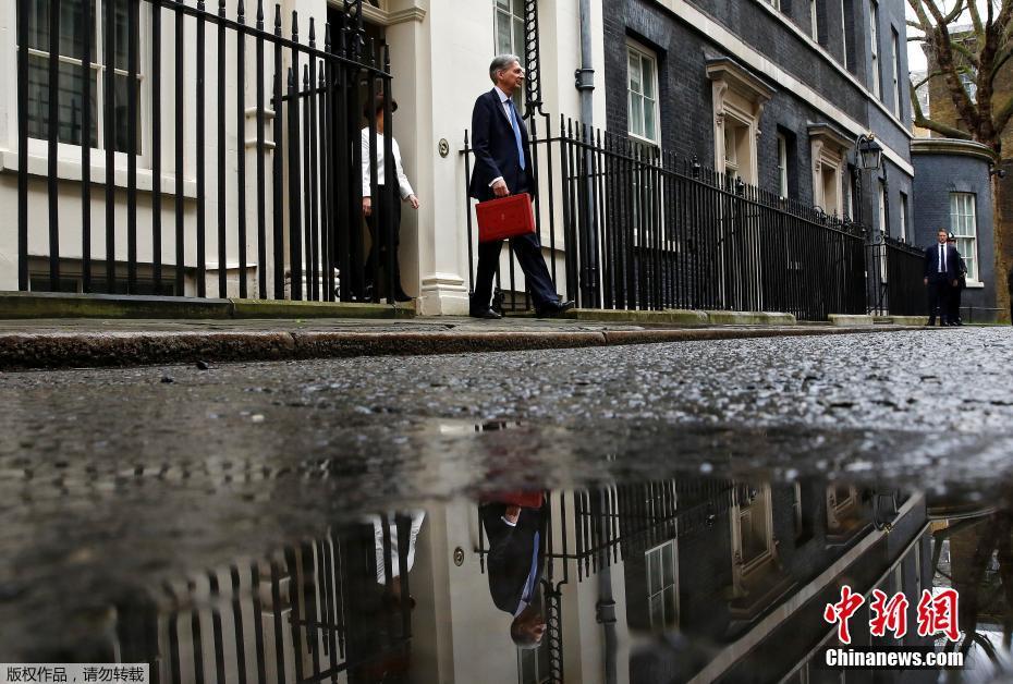 英国公布脱欧预算报告 记者趴水坑拍照也是够拼