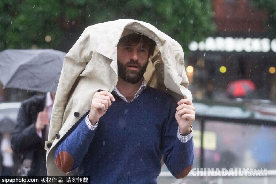 英国伦敦雨天狂风大作 民众出行雨伞被吹翻