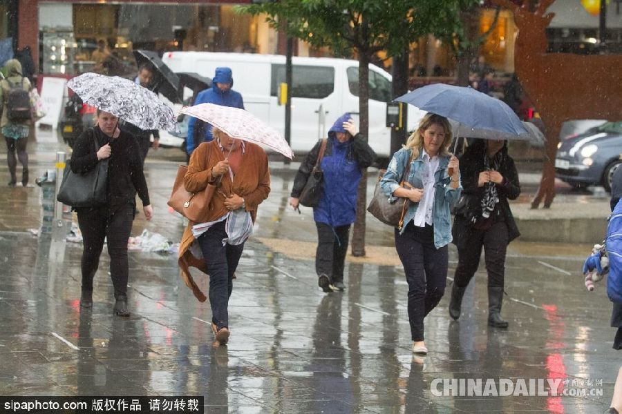 英国伦敦雨天狂风大作 民众出行雨伞被吹翻
