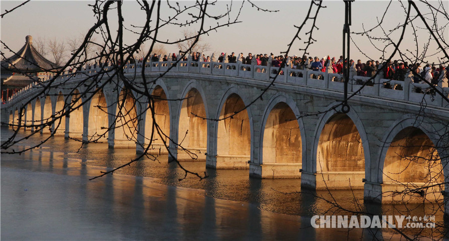 游客在颐和园欣赏十七孔桥金光穿洞美景。 中国日报记者 姜东 摄 中国日报12月21日电 2017年12月21日日落时分,北京颐和园十七孔桥出现金光穿洞美景,吸引许多游客前来观赏。 (编辑:涂恬 黄河流)